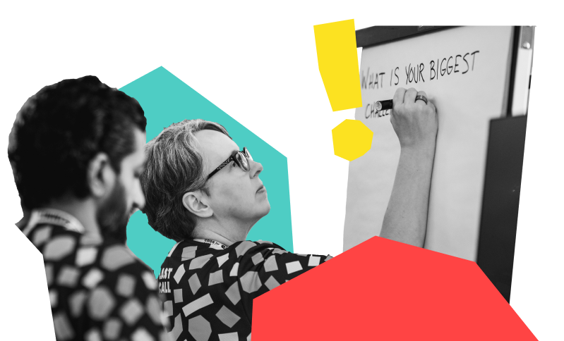 image of two staff members, one watching the other writing on a large post it note
