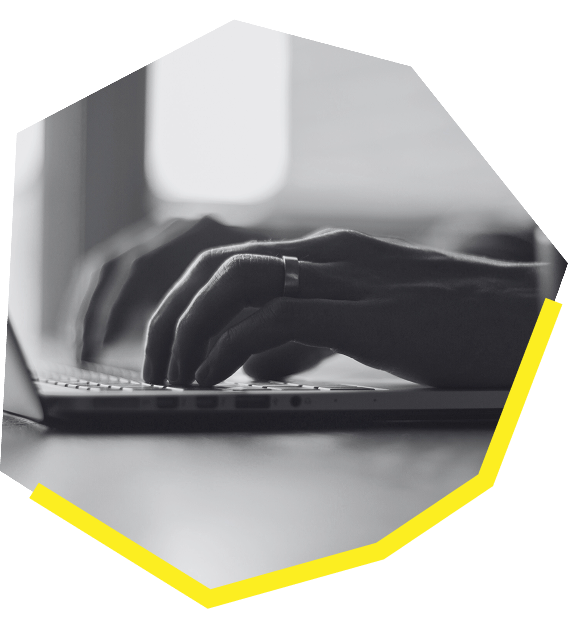 Close-up of hands typing on a laptop keyboard, shown in black and white with a yellow geometric accent.