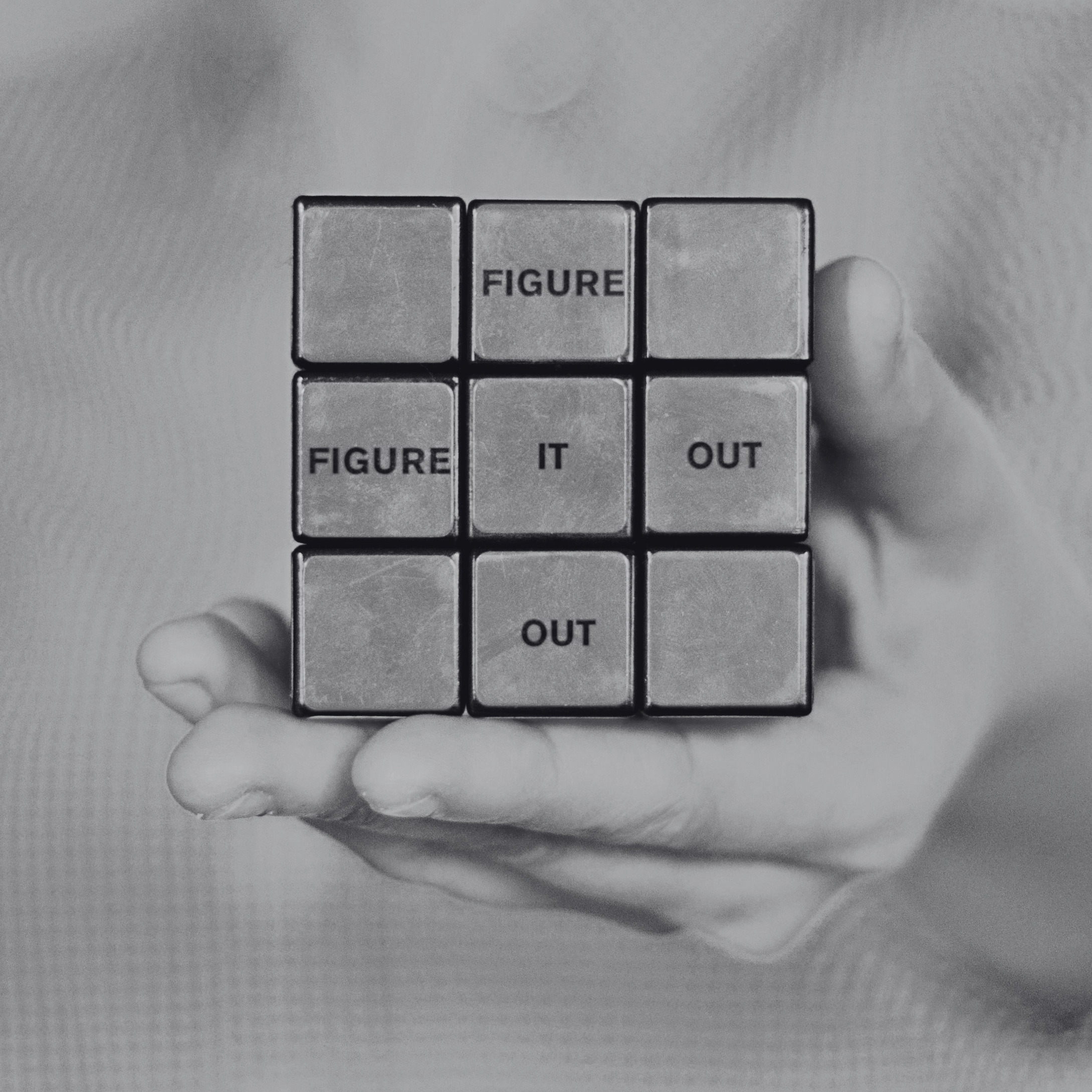 A black and white photo of a rubix cube with the words figure it out inside the squares.