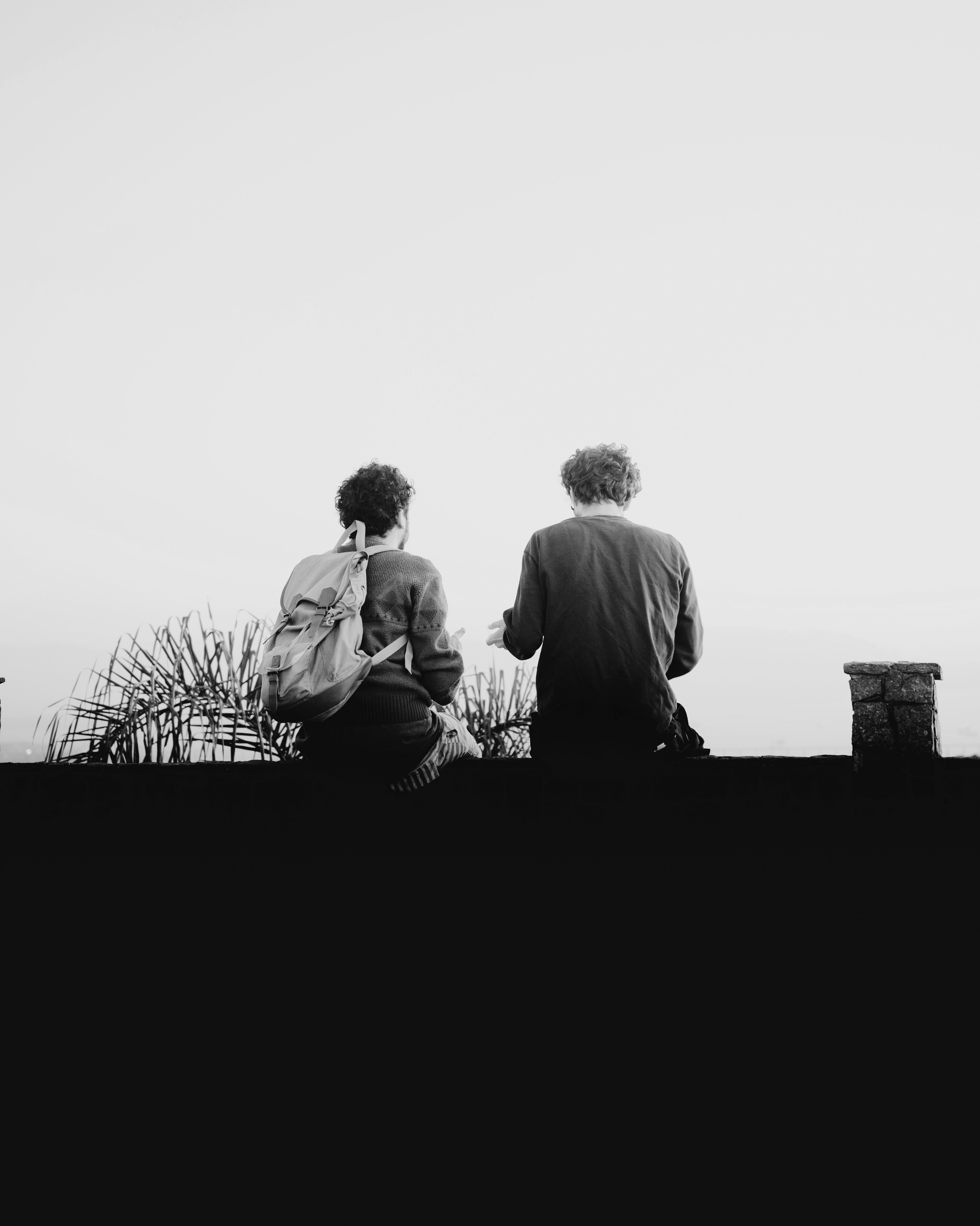 A black and white photo of two people sitting on a ledge.
