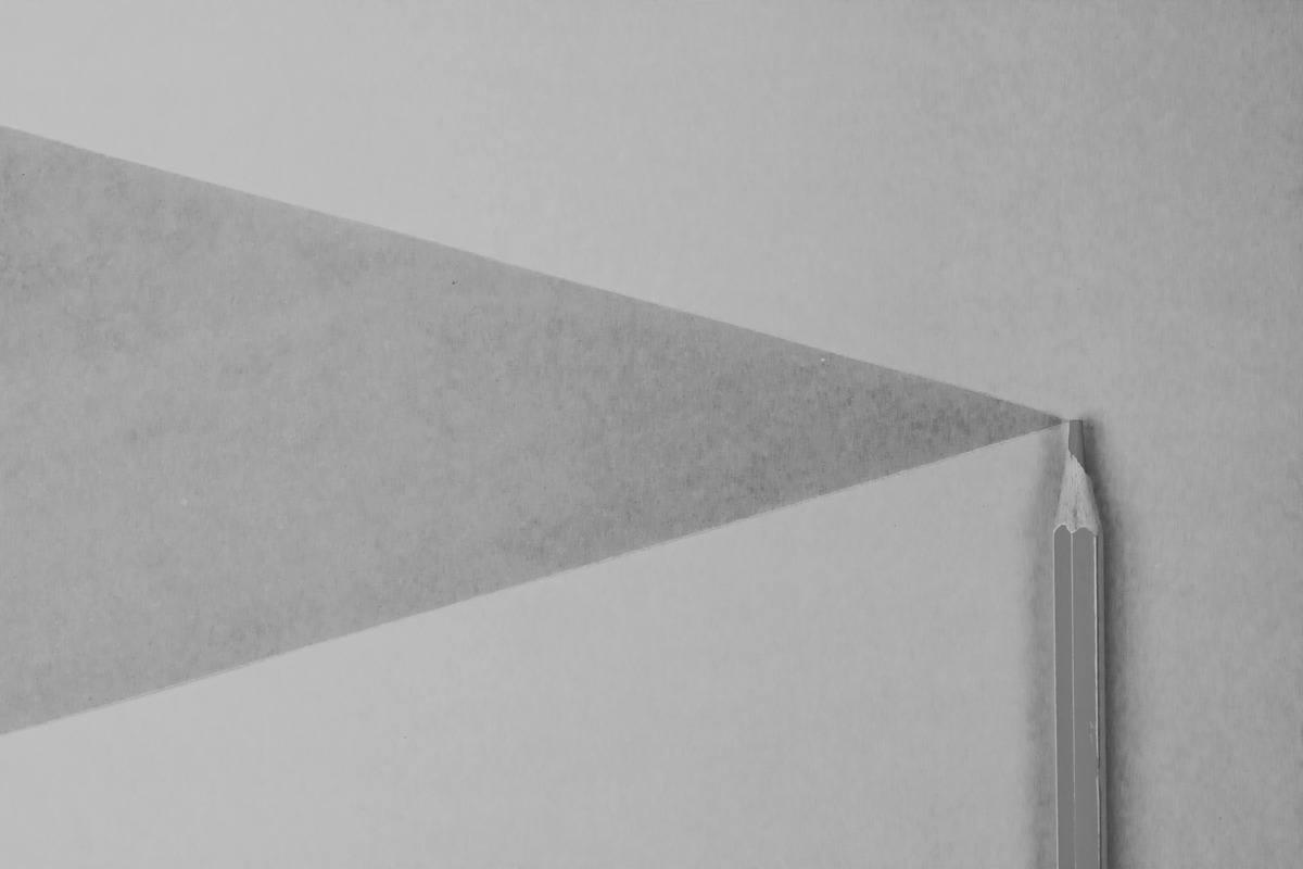 Gray pencil on white paper casting a triangular shadow.