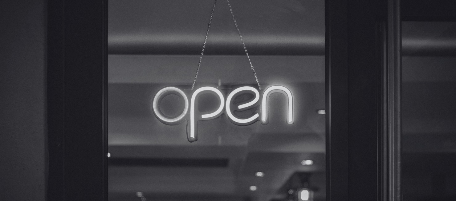 Black and white photo of an LED open sign hanging in a window.