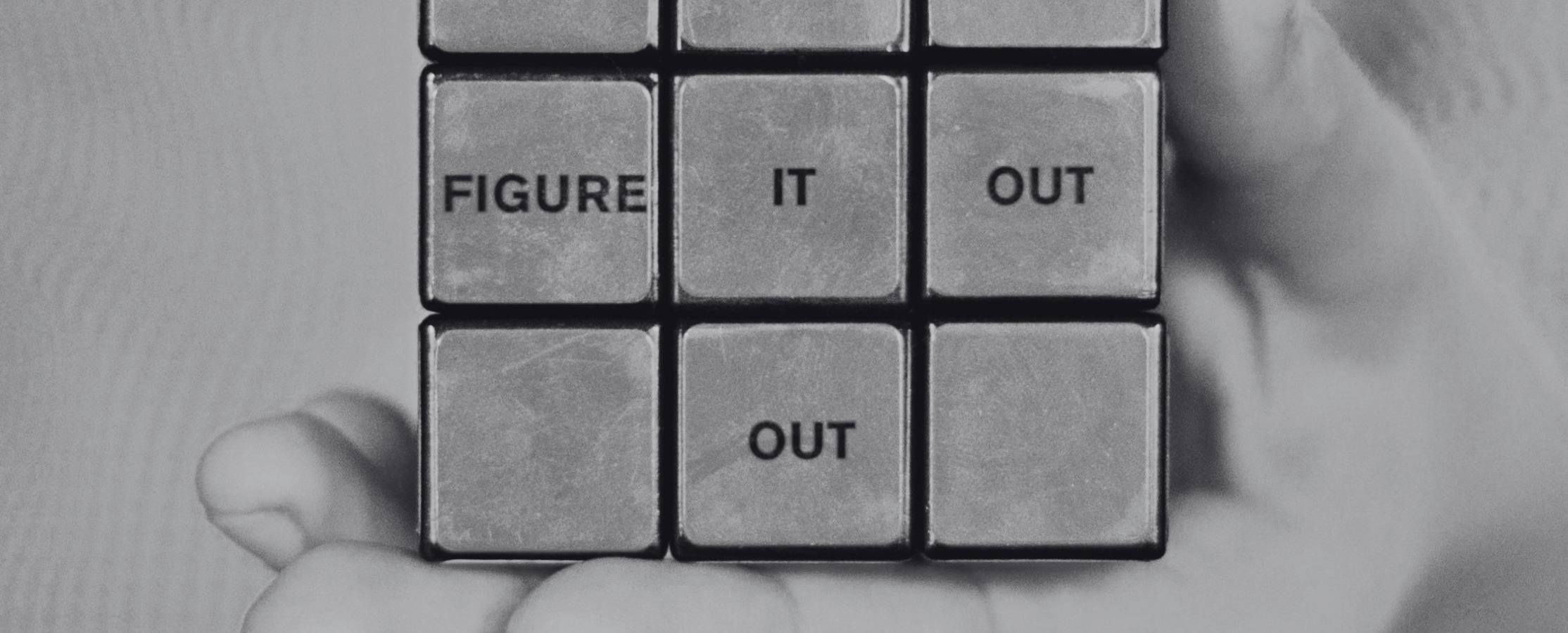 A black and white photo of a rubix cube with the words figure it out inside the squares.