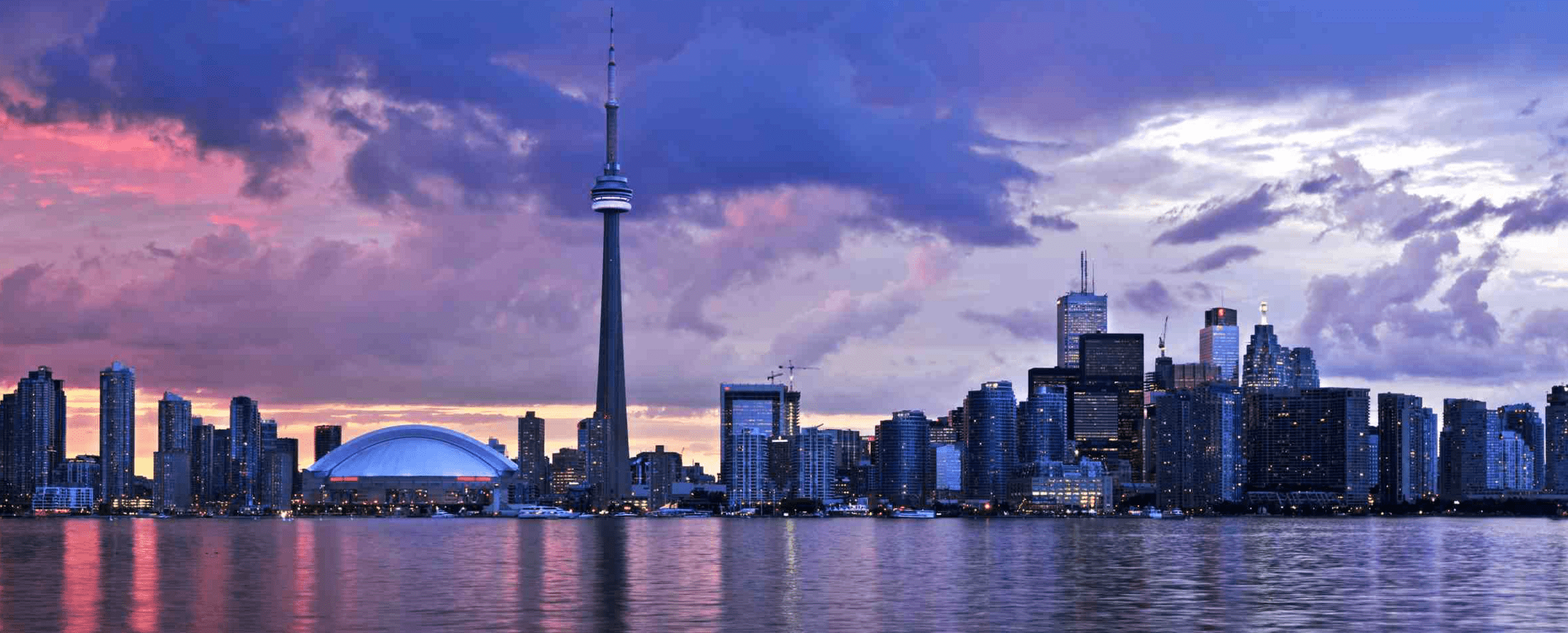 Toronto skyline against a colorful clouds at sunset.