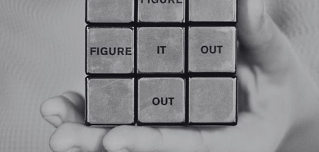 A black and white photo of a rubix cube with the words figure it out inside the squares.