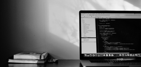 A black and white image of a laptop showing code on the screen