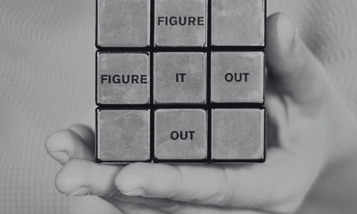 A black and white photo of a rubix cube with the words figure it out inside the squares.