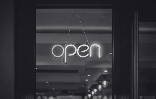 Black and white photo of an LED open sign hanging in a window. 