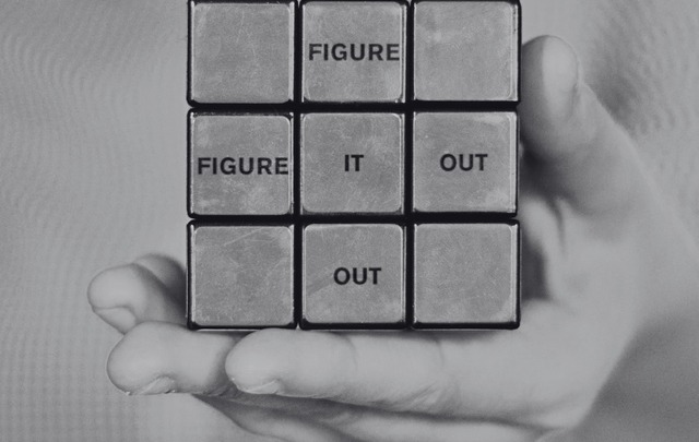 A black and white photo of a rubix cube with the words figure it out inside the squares.
