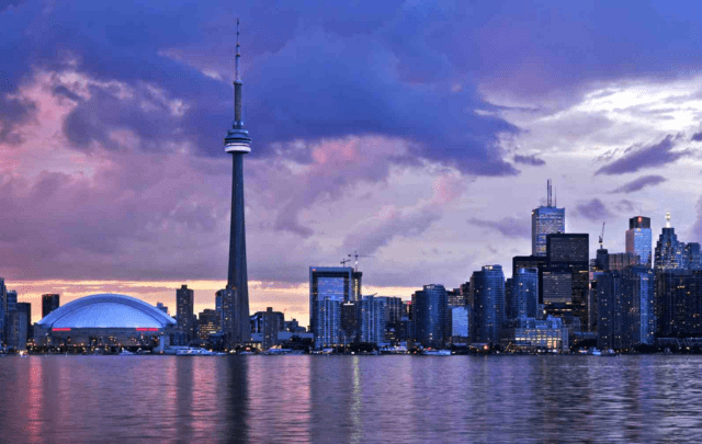 Toronto skyline against a colorful clouds at sunset.