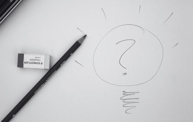 black and white image of a pencil and a drawing of a question mark inside a light bulb.