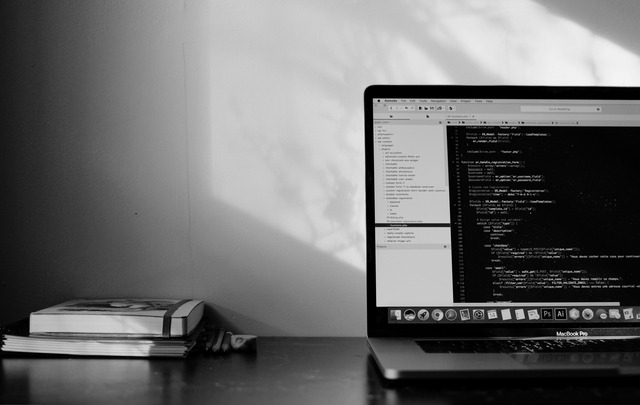 A black and white image of a laptop showing code on the screen