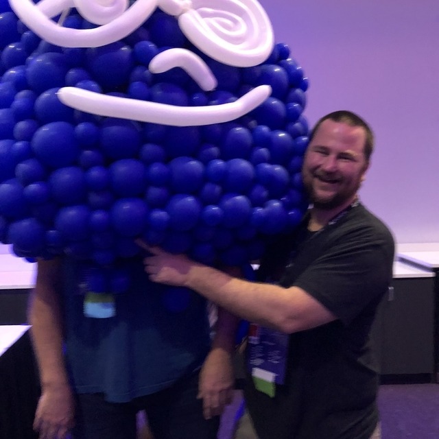 Two camp attendees posing while one of them wears a Drupal drop costume made out of balloons
