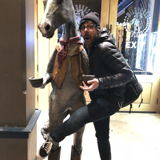 jayme posing with a horse statue at an after party