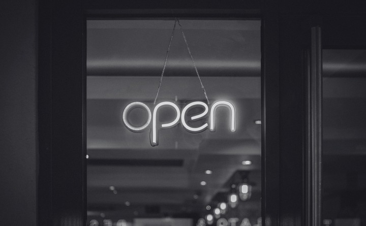 Black and white photo of an LED open sign hanging in a window.